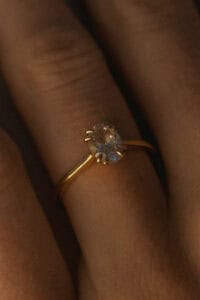 Gold ring with a sparkling diamond on a finger.